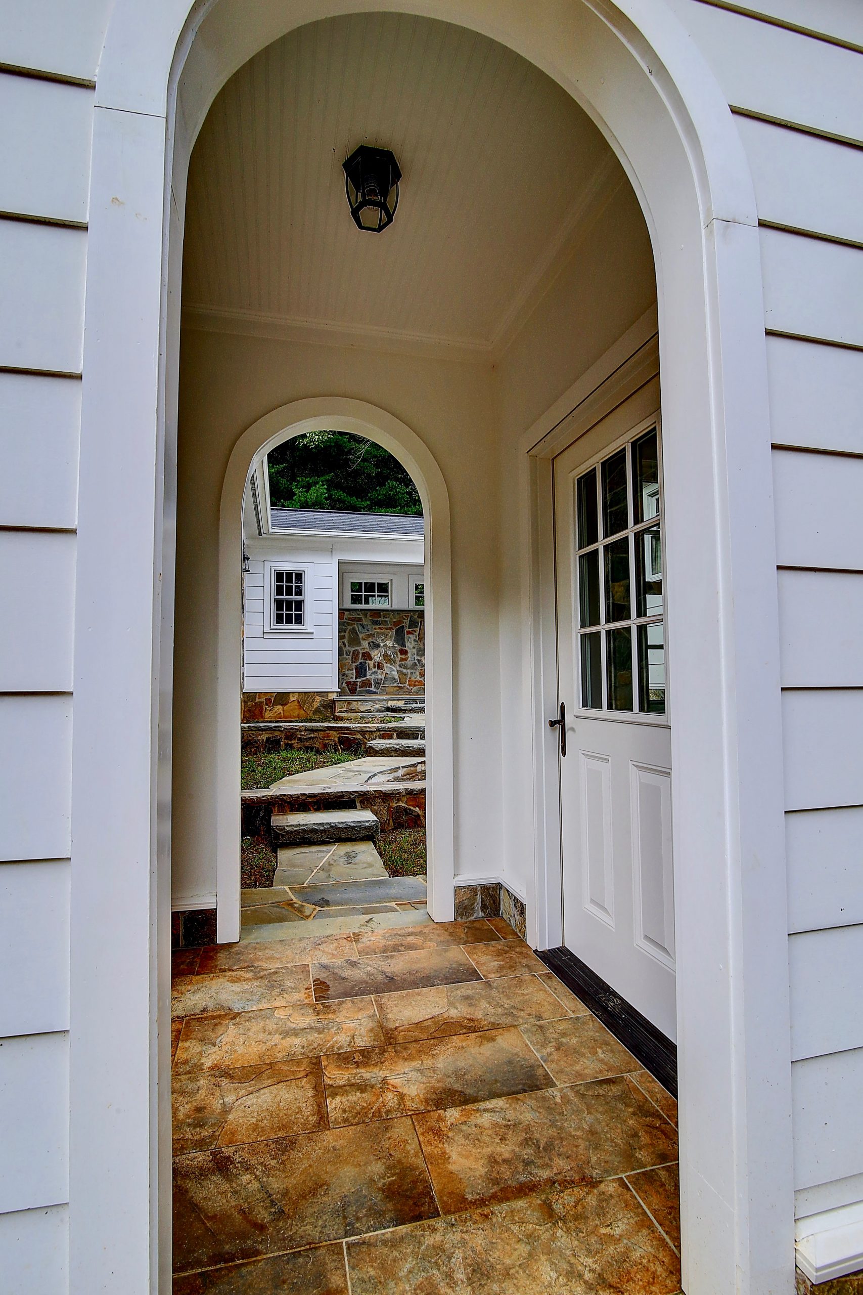 Exterior entryway with arched doorways and tiled stone floor