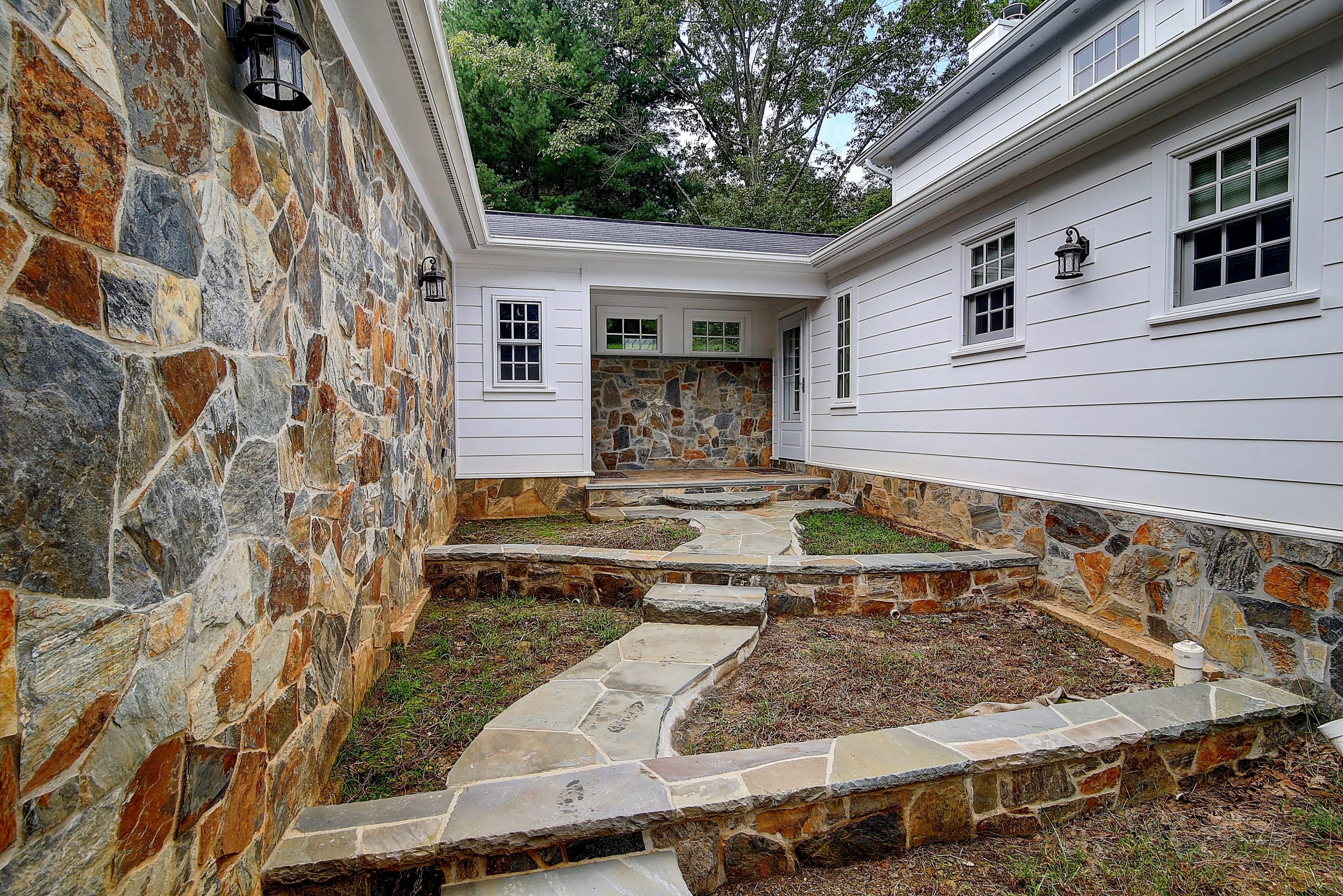 tiered courtyard outside of a historical home with natural stone walls and pathway