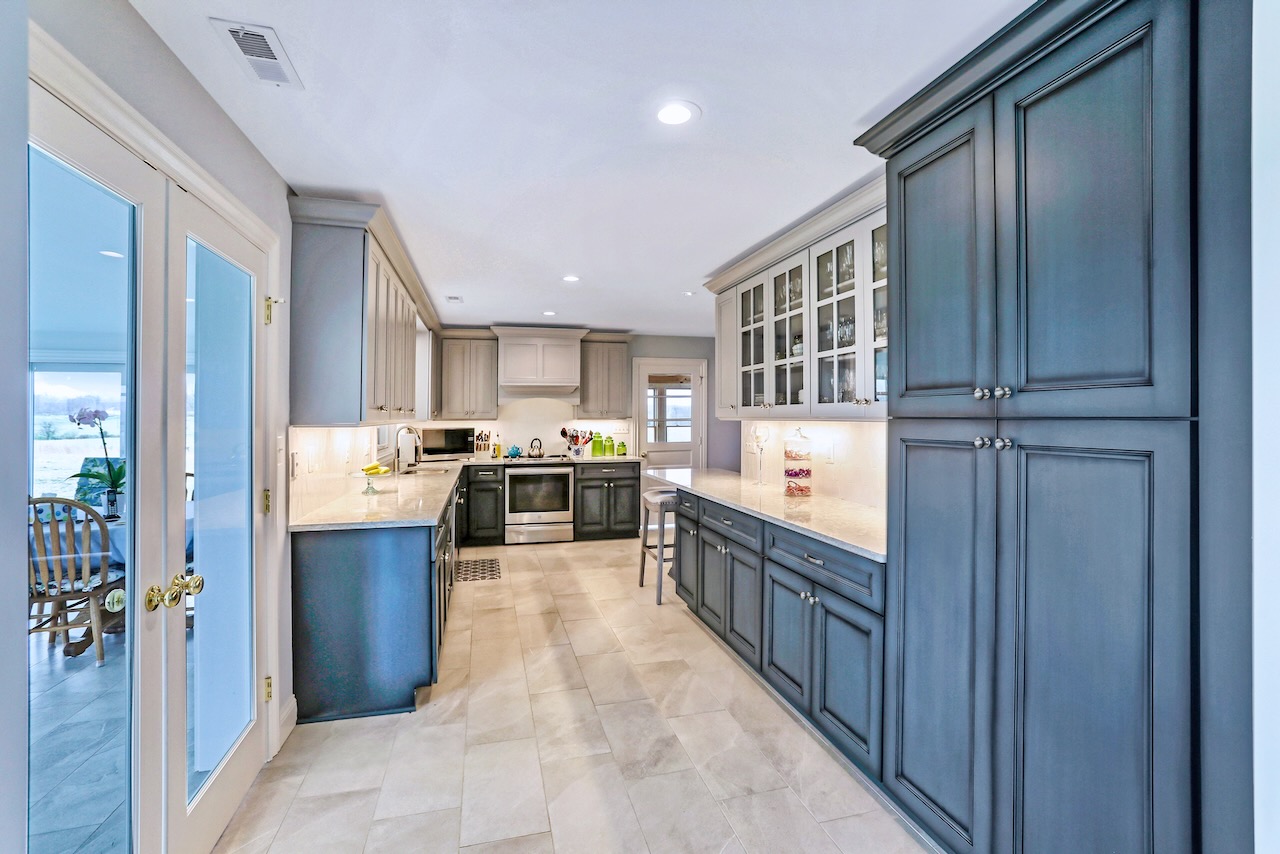 long kitchen with slate blue cabinets and white floor