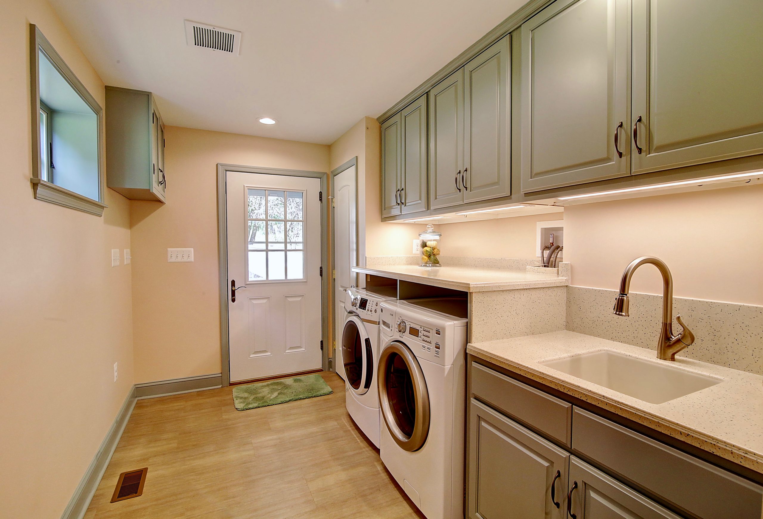 renovated laundry room with green cabinets