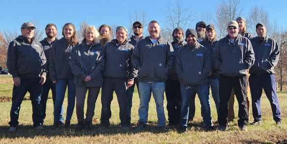 Group of Lauten employees wearing matching Lauten Design jackets posing for a group photo outdoors