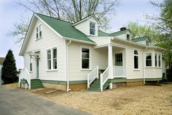 exterior of renovated white, wooden home with a green, metal roof