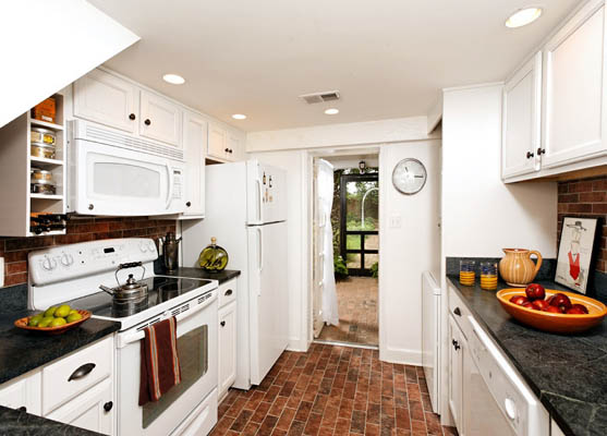 renovated galley-style kitchen with brick floor