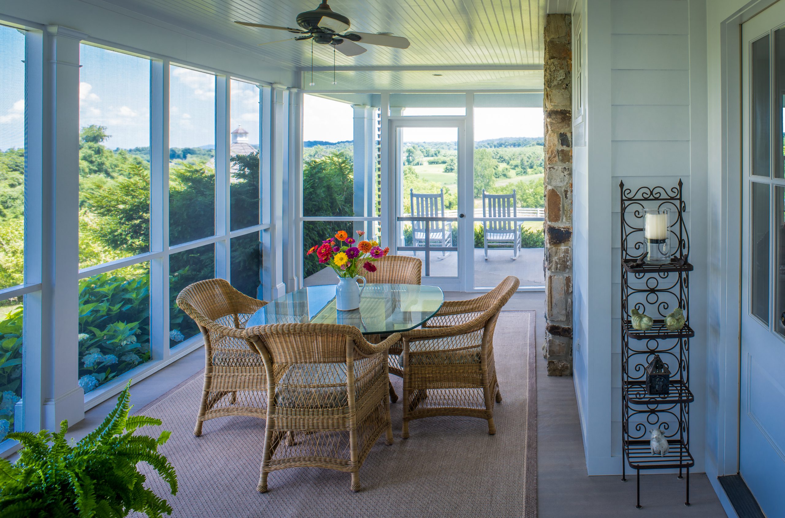 screened porch with glass-topped outdoor dining table and wicker chairs
