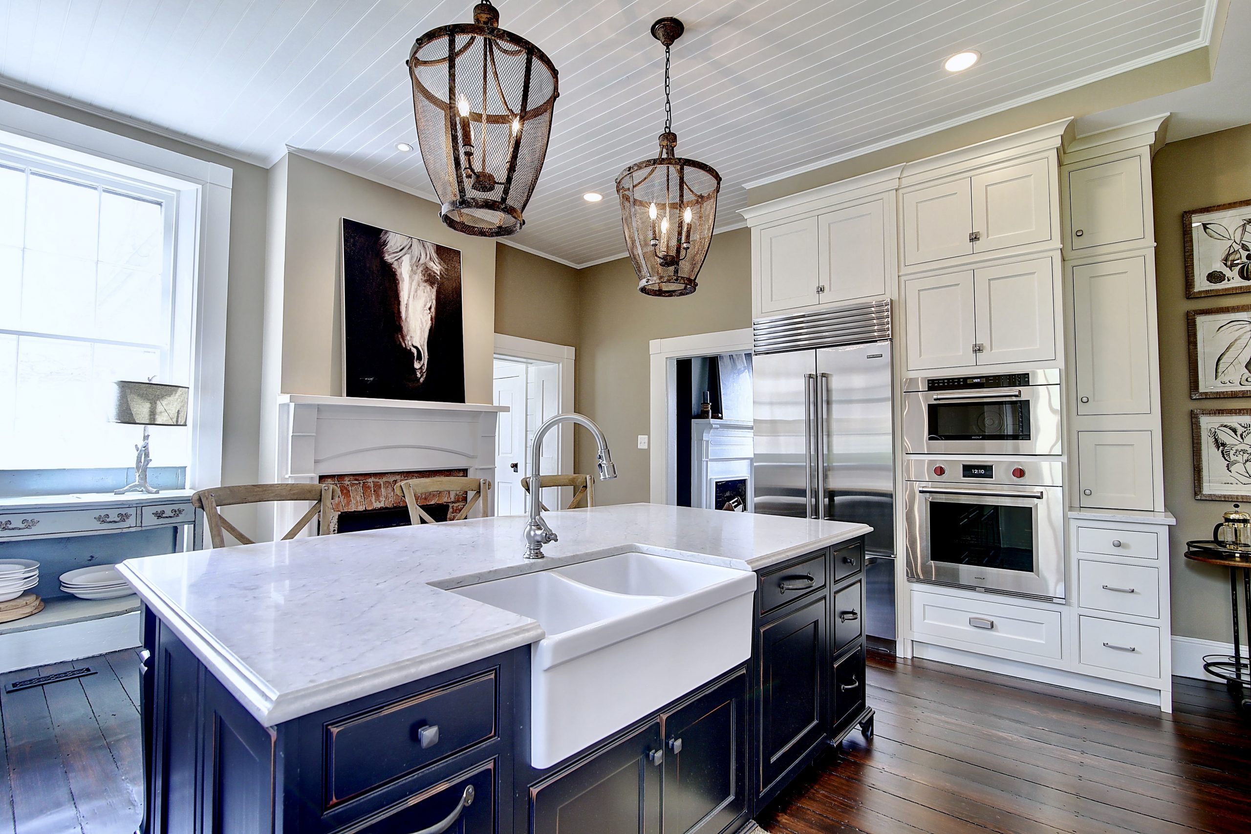 renovated kitchen with white cabinets and navy blue center island with white ceramic double sink