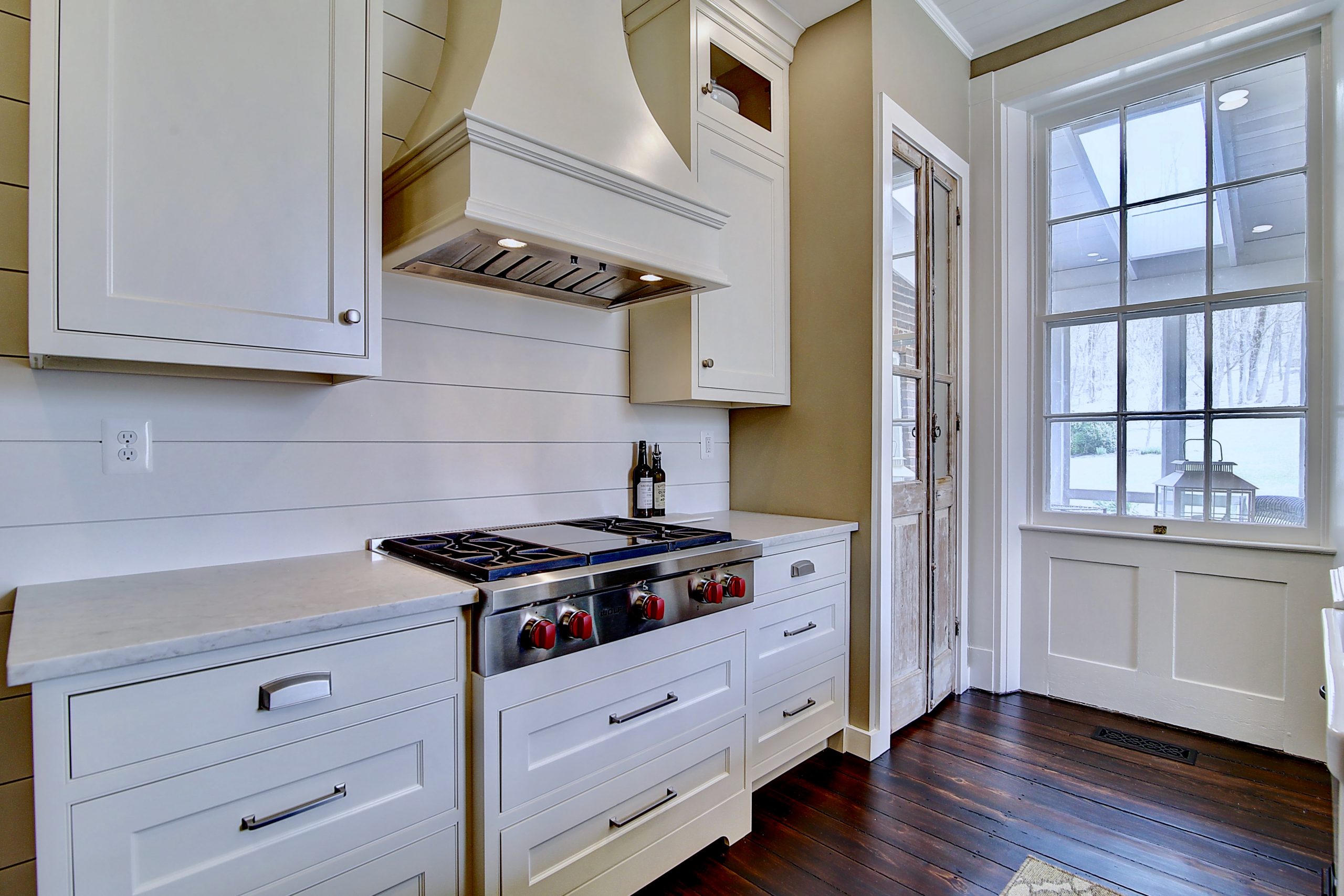 renovated kitchen with modern white cabinets and range hood