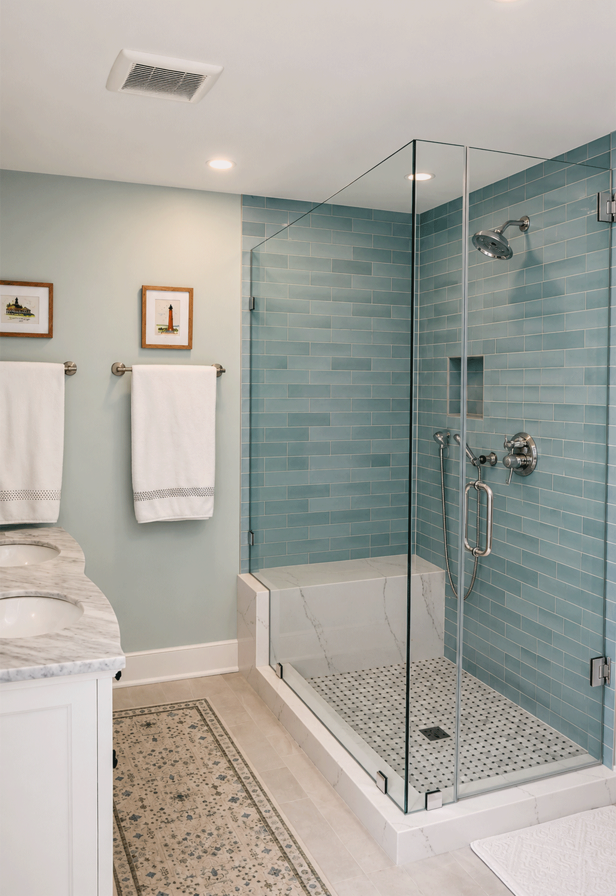primary bathroom with a marble top vanity, a marble engineered stone shower seat/ curb, aqua blue subway tile and polished chrome fixtures